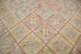 Hand-woven vintage Jijim rug showing faded cinnabar, beige, and pale geometric diamond patterns.