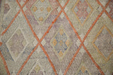 Hand-woven geometric diamond texture of a vintage Jajim rug with softened cinnabar and pale tones.