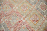 Hand-woven Jajim rug detail: geometric diamond pattern in softened cinnabar, beige, and pale tones.