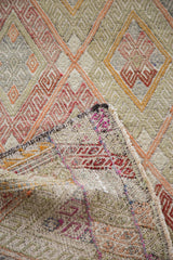 Hand-woven vintage Jajim rug folded, revealing lattice diamond pattern and soft faded colors.