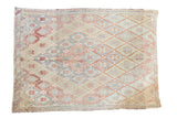 Vintage Jajim rug with geometric diamond pattern in faded reds, beiges, and soft blues.