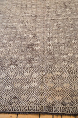 Distressed Jijim runner detail: intricate charcoal, ivory, brown geometric pattern and decorative border.