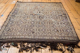 Distressed Jijim rug's intricate geometric pattern, nuanced weaving, and dark wool fringe.