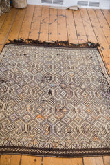 Intricate geometric patterns and dark wool fringe detail on a distressed Jijim rug.