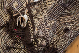 Textured geometric weave of a distressed Jijim rug, showing dark brown fringe.
