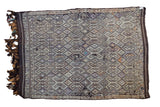Distressed hand woven Jijim rug featuring intricate geometric motifs in textured dark brown and muted hues.