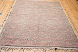 Tightly woven geometric pattern and fringe on a vintage Jajim rug, featuring faded red and charcoal.