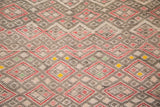 Vintage Jajim rug's geometric pattern: faded red, charcoal, ivory, and small yellow accents.