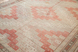 Geometric diamond guls in faded cinnabar red and ivory tones on a vintage Jijim carpet.