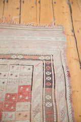 Geometric diamond guls and striped borders of the vintage Jijim carpet in ivory and faded cinnabar.