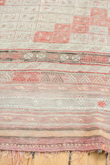 Fringe and geometric banded patterns in faded cinnabar, ivory, and silver on a vintage Jijim rug.