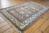 Corner of vintage Indian rug featuring aqua blue, ivory Arts & Crafts border and red pearl detail.