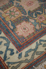 Detail of vintage Indian rug, showing peach rose palmettes, red pearl, and sprawling aqua borders.