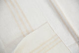 Folded upcycled kilim carpet showcasing textured ivory and near white stripes.