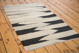Textured hand-woven Kilim displaying black and natural beige zigzag stripes.