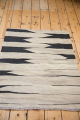 Hand woven Kilim rug featuring a Southwestern black and beige geometric pattern.