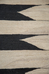 New Kilim rug's hand-woven texture with black and natural beige geometric arrow pattern.