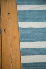 Hand-woven Kilim rug showing striated sky blue and ivory stripes and texture.