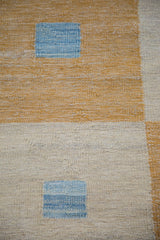 Kilim rug's geometric square-on-square pattern in saffron gold, ivory, and abrash blue.