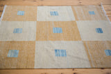Detail of the kilim weave with saffron gold, ivory, and abrash blue square motifs.