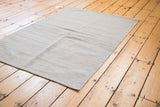 New Kilim rug's corner, showcasing its unique textured flat weave in neutral ivory and grey.