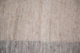 Woven wool texture of the Kilim carpet, light brown meeting grayish brown border.