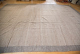 Soft, flat-woven light brown Kilim rug with a contrasting grayish brown border.