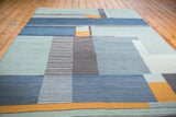 Hand woven abstract kilim with geometric blue, charcoal, and saffron gold blocks.