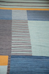 Abstract hand-woven kilim detail, geometric blocks, stripes in blue, charcoal, saffron.