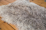 Soft, curly Angora wool throw pelt showing a blend of natural grey and cream tones.