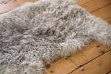 Fluffy Angora wool throw showcasing its soft, curly grey and cream texture.