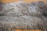 Curly, fluffy texture of a luxurious Angora wool throw in natural gray tones.