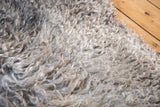 Fluffy angora wool pile texture with soft curly strands in natural gray hues.