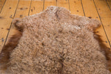 Fluffy light brown angora wool pile texture with its natural pelt edge.