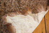 Fluffy brown angora wool texture and soft beige leather backing of the throw pelt.