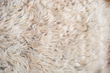 Luxurious fluffy angora wool texture of the cream and beige throw rug.