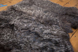 Luxurious curly dark gray angora wool throw with fluffy texture.