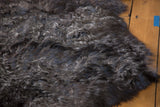 Luxurious dark gray angora wool pelt rug texture close-up.