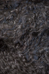 Luxurious deep charcoal angora throw rug with fluffy, curly wool texture.