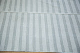 Flat-woven Kilim rug with light ivory and gray stripes, highlighting a horizontal seam.
