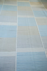 Decorative seaming and alternating blocks on a hand-woven blue and beige Kilim carpet.