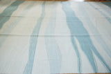 Textured hand-woven kilim carpet with abstract powder blue and ivory water channels.