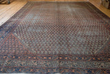 Distressed Mir Serbend carpet with faded blue and light red allover pattern.