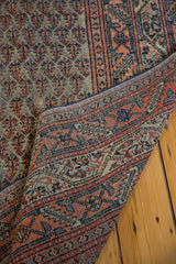 Distressed Mir Serbend Persian rug showing faded main field and contrasting blue-red border.