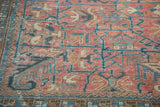 Distressed rose and charcoal blue geometric patterns with compartmentalized outlines on a vintage Heriz.