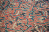 Vintage Heriz carpet's distressed low pile texture with geometric rose and charcoal blue motifs.