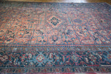 Distressed Vintage Heriz carpet detail, showing muted rose, charcoal blue geometric border and field.