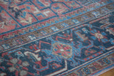 Textured detail of vintage Heriz carpet, low pile, geometric pattern in rose and charcoal blue.