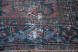 Heriz carpet with low pile, exposed foundation, muted rose and charcoal blue patterns.
