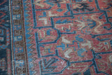 Distressed Heriz rug texture, showing faded rose and charcoal blue geometric patterns.